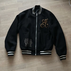 Svart varsity jacka Asos - Säljer en snygg mörkblå/svart varsity bomberjacka med broderad bokstav på bröstet från Asos. Jackan har dragkedja och ribbade muddar i svart och vitt. Perfekt för höst och vår, och ger en stilren look till vardagsoutfiten. Strlk xs men är mer som S