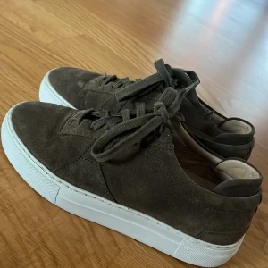  mockasneakers från Axel Arigato stl 36 - Säljer ett par snygga olivgröna  sneakers i mocka från Arigato. De har en vit sula och klassisk snörning. Perfekta för en avslappnad stil och passar till både jeans och chinos. Skorna är i bra skick!