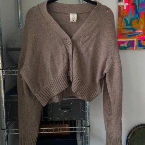 Beige stickad kofta - Säljer en superfin beige stickad kofta i croppad modell från Carin Wester. Den har stora knappar framtill och långa ärmar. 