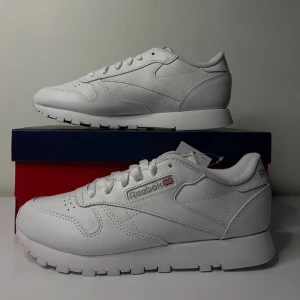 Vita Reebok Classic sneakers - Säljer ett par vita Reebok Classic sneakers i skinn. De är i nytt skick och har en stilren design med snörning. Perfekta för både vardag och träning. Storlek dam 36. Kommer med originalförpackning.