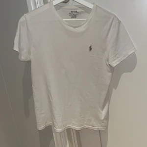T-shirt - En vit Polo Ralph Lauren T-shirt i storlek XS. Polo märket på tröjan är lite orange brun blandat.