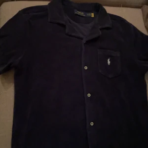 Mörkblå skjorta från Ralph Lauren - Säljer en snygg mörkblå skjorta från Ralph Lauren. Skjortan är i matrialet frotté. Den är i bra skick och har bara används ett fåtal gånger. perfekt för både vardag och fest. Skjortan köptes förra sommaren för 1800kr, mitt pris 700kr✅ Det är bara att höra av sig vid några frågor!! MVH Emil 