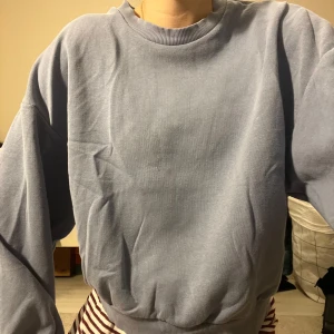 Blå sweatshirt - Mysig blå sweatshirt i normal passform. Perfekt för kyliga dagar. Den har långa ärmar och ribbade muddar vid ärmslut och nederkant. Har en fläck längst ner men syns knappt och är fortfarande i bra skick. Perfekt för vardagsbruk!
