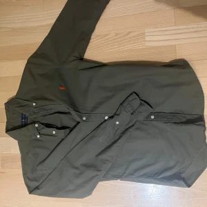 Grön skjorta från Ralph lauren ( storlek S )  - Säljer en fet olivgrön skjorta från Ralph Lauren i slim fit. Storleken är S och passar så. Den är använda fåtal gånger och är i 9/10 skick🙌🏼. Pris kan diskuteras! Frakt på 1-2 dagar ✅📦. 