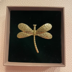 Guld ring trollslända  - Superfin guldfärgad ring formad som en trollslända. Den har detaljerade vingar och en elegant design som verkligen sticker ut. Perfekt accessoar för att ge lite extra till din outfit. Passar både till vardags och festliga tillfällen. Helt ny! (Låda tillhör inte)