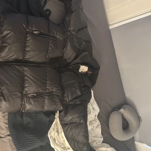 Svart dunjacka från Moncler - Säljer en svart gammal moncler jacka från 60-70 talet (vintage och ärvd av äv min morfar) ”insidans tecknade serie detalj var borttagen ett tag sedan för att den höll på att komma av efter att den virdrörde ett vasst föremål ett tag sedan” bild#5, jackan går därav inte heller att scanna med mobil men det finns dock artikel nummer på jackan,  ifall det är något man vill så kan man kp och så visar jag bild så får ni söka upp och pris kan även diskuteras, jackan har sentimentalt värde o ä vintage 
