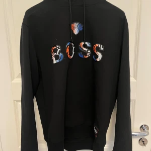 Svart tracksuit från Boss X NBA - Säljer en svart tracksuit från Boss. Den har en klassisk passform med långa ärmar och en bekväm huva. Perfekt för en avslappnad stil eller för att hålla sig varm under kyliga dagar. Passar både till vardags och för sportiga aktiviteter.