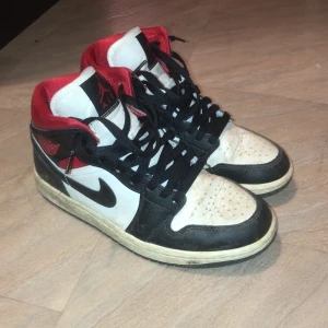 Nike Air Jordans i svart, vitt och rött - Säljer ett par klassiska Nike Air Jordans i svart, vitt och rött. Skorna har snörning och är i bra skick med en cool design som passar perfekt för både vardag och fest. De är bekväma och stilrena, perfekta för dig som vill ha en sportig look.
