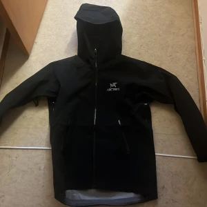 Svart arcteryx jacka  - Hej, säljer min svarta arcteryx jacka, perfekt för skidåkning och används ofta för en snygg skön skaljacka. Har ett material som får vattnet att rinna av bokstavligen, har massa dragkedjor för att vädra när man åker skidor, inte använd utanför dörren, köpt i mars men han inte åka skidor med den.  