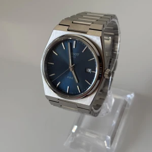 Tissot PRX - • Modell: Tissot PRX • Storlek: 40mm • Referens: T137.410.11.041.00 • År: 2023 • Skick: Mycket Bra • Medföljer: Fullset med extra original läder och gummiband + originalpåse