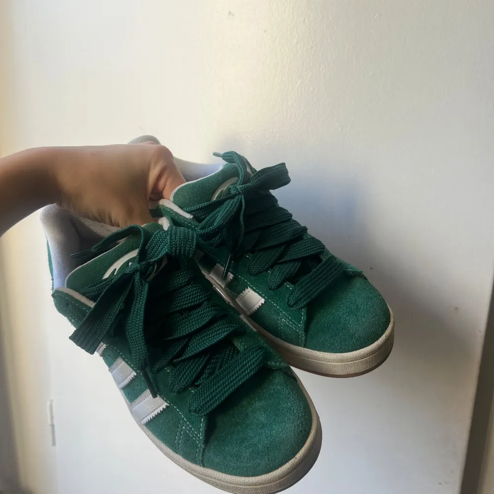 Säljer ett par snygga gröna Adidas Campus sneakers i mocka. De har de klassiska vita ränderna på sidan och en bekväm passform. Perfekta för både vardag och fest! Skorna är i bra skick och endast använda 1 gång. . Skor.