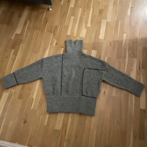 Grå stickad tröja från Zara - Säljer en snygg grå stickad tröja från Zara i storlek M. Tröjan har en hög krage och långa ärmar. Använd fåtal gånger. Inga spår av användning. Hör av dig om du har några funderingar 💕