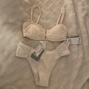Bikini  - Creamvit bikini över och under del i nyttskick, helt helt oanvänt. Säljer den då jag köpte en annan och får ingen användning av denna och går ej att lämna tillbaka. Storlek 38 i båda delarna och 250kr för båda. (Nypris: 328kr). 