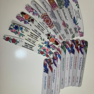 Nagelfilar med blommönster - Säljer ett set med nagelfilar i olika blommiga mönster. De har en kornighet på 100/180, perfekt för att forma och jämna ut naglarna. Färgglada och stiliga, dessa nagelfilar är både praktiska och snygga att ha i necessären.