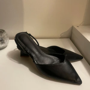 Svarta klackskor med spetsig tå - Snygga svarta klackskor i skinn med en elegant spetsig tå. Perfekta för både fest och vardag. De har en låg klack som ger komfort hela dagen. Passar bra till både klänning och jeans!