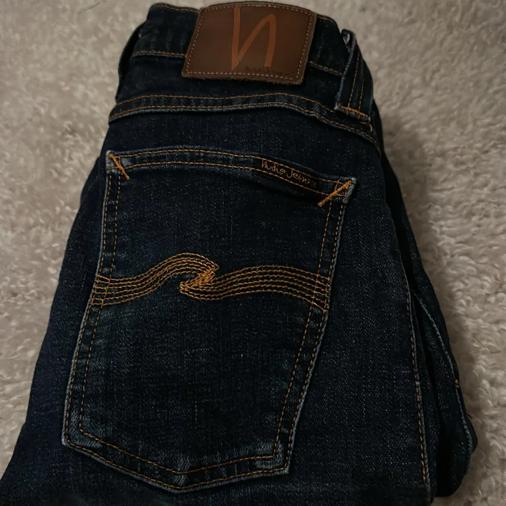 Säljer ett par snygga mörkblå jeans från Nudie Jeans. De har en klassisk femficksdesign med snyggt broderad bakficka och en läderpatch med logga. Perfekta för både vardag och fest🌟9/10 skick 🌟. Jeans & Byxor.