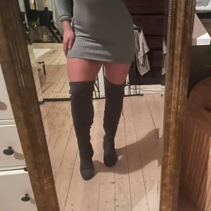 Grå overknee stövlar med snörning  - Säljer ett par snygga grå overknee stövlar i mocka. De har en bekväm klack och är perfekta för höst och vinter. Stövlarna är i mycket bra skick och passar både till vardags och fest. Perfekt för att hålla stilen när det blir kallare!