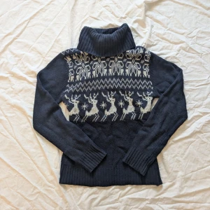 Mörkblå stickad polotröja med renmönster - Säljer en mysig mörkblå stickad polotröja från H&M Basic. Den har ett charmigt vitt renmönster över bröstet och långa ärmar. Perfekt för kalla vinterdagar och julmys! 🦌❄️