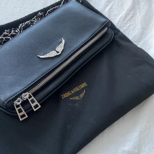 Svart axelväska från Zadig & Voltaire - Säljer min sjukt snygga Zadig & voltair väska😍😍då den inte kommer till mycket användning. Den är i bra skick tråden i kedjan har åkt ut lite men de syns inte och går att fixa. Den är använd få tal gånger  och galet snyggt till allt🙏💕💕⚠️TAR BARA SWISH ⚠️