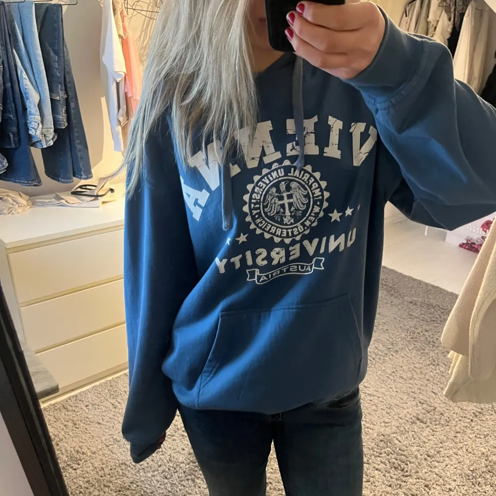 Säljer en snygg blå hoodie med vitt tryck framtill. Den har en stor ficka på magen och en bekväm passform. Köpt i Wien!!!💙💙. Hoodies.