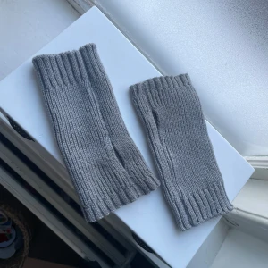 Grå stickade handledsvärmare - Säljer ett par grå stickade handledsvärmare. De är ribbstickade och perfekta för att hålla handlederna varma under kyliga dagar. Passar bra till både vardags och mer uppklädda tillfällen. Supermysiga och stilrena!🤍