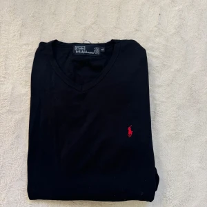 Svart långärmad tröja från Ralph Lauren - Svart v-ringad tröja från Polo Ralph lauren i storlek XL men är ganska liten i passform. Tröjan är unisex och köpt för omkring 1000kr 