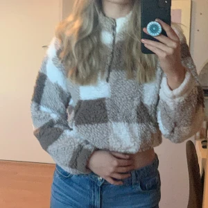 Mysig rutig fleece från Shein - Säljer en supermysig och varm fleece från Shein i storlek M. Den har ett snyggt rutigt mönster i beige och vitt, perfekt för kalla dagar. Tröjan är croppad och har en dragkedja framtill. Perfekt för höst och vinter! 🍂❄️