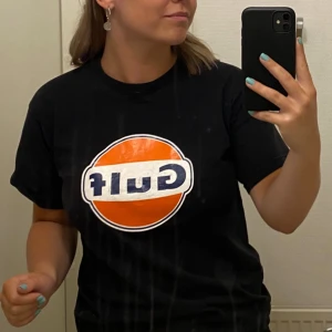 Svart t-shirt med Gulf-logga - Säljer en svart t-shirt med den klassiska Gulf-loggan i orange och blått på framsidan. Storlek S. 