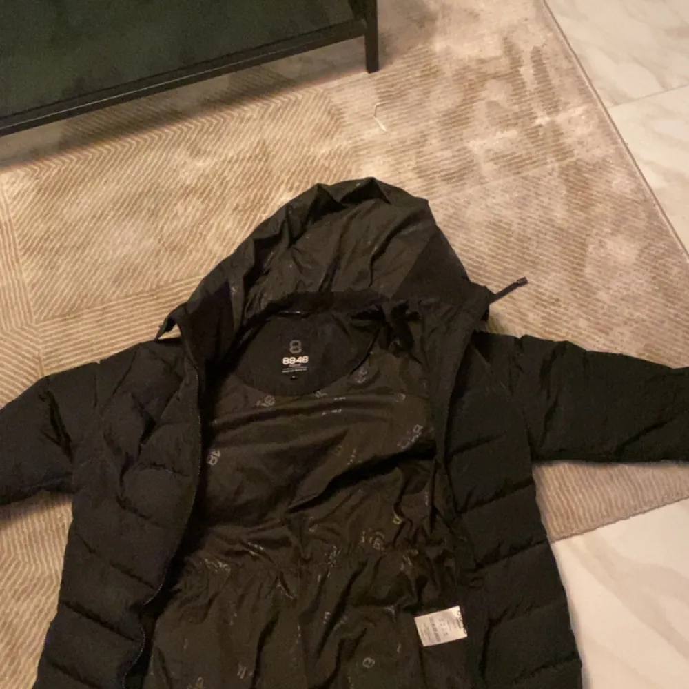 Säljer en svart dunjacka från 8848 Altitude i storlek 42. Jackan är perfekt för kalla vinterdagar med sin pufferstil och långa ärmar. Den har en dragkedja framtill och är i mycket bra skick. Perfekt för både vardag och utomhusaktiviteter!. Takit.