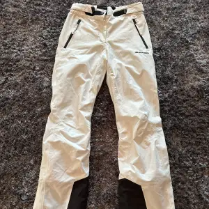 Vita skidbyxor från Hilfiger i mycket bra skick. De har svarta detaljer och dragkedjor vid fickorna. Tightare modell, bootcut. Byxorna är högmidjade och perfekta för vinterns äventyr i backen. Justerbar i midjan för perfekt passform. Passar perfekt för både skidåkning och andra vinteraktiviteter! ❄️