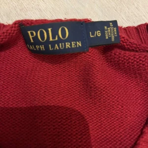 Röd tröja från Ralph Lauren - Säljer en snygg röd tröja från Ralph Lauren. Den är i bra skick och har en klassisk design med rund hals och långa ärmar. Perfekt för både höst och vinter. Den ikoniska loggan är broderad på bröstet. Passar perfekt för en stilren look!