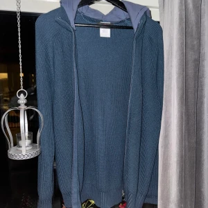 Blå stickad jacka från Gran Sasso - Säljer en riktigt fet blå stickad jacka från Gran Sasso. Den har den ikoniska zippern framtill och en quiltad huva för extra stil och värme. Perfekt för höst och vår!🙌🏻Hör av er om ni vill ha fitpics eller liknande. Storlek 52 passar L skulle jag säga!