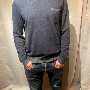 Mörkblå tröja från Replay - Säljer en snygg mörkblå tröja från Replay i bra skick. Den har en liten bröstficka och ribbade detaljer vid hals och ärmslut. Perfekt för både vardag och lite finare tillfällen. Passar bra till jeans för en avslappnad look. Storlek XL men passar M/L. Modellen är 178