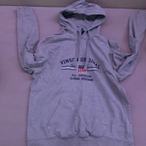 Grå hoodie från Vinson Signal - Säljer en grå hoodie från Vinson Signal med tryck på bröstet. Den har en klassisk känguruficka och justerbar huva med dragsko. Perfekt för en avslappnad stil och passar bra till både vardag och chill. Skön och bekväm att ha på sig!