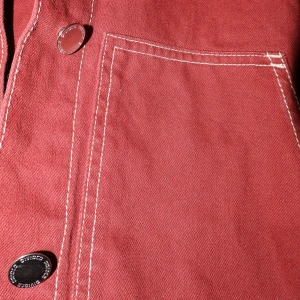 Röd croppad jacka med knappar - Säljer en snygg röd croppad jacka med vita sömmar och knappar. Jackan har en klassisk krage och två stora fickor fram. Perfekt för vår och sommar! 🧡