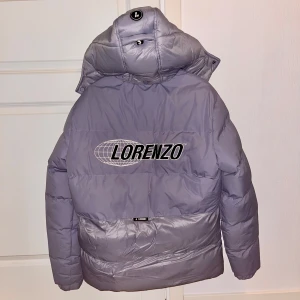 Grå pufferjacka från Lorenzo Veratti - Säljer en snygg grå pufferjacka från Lorenzo Veratti 🥶 i storlek M. Jackan har en praktisk dragkedja och en avtagbar huva. Perfekt för kalla vinterdagar med sin varma och vadderade design. Den har också två fickor med dragkedja för säker förvaring. Passar både till vardags och lite finare tillfällen.
