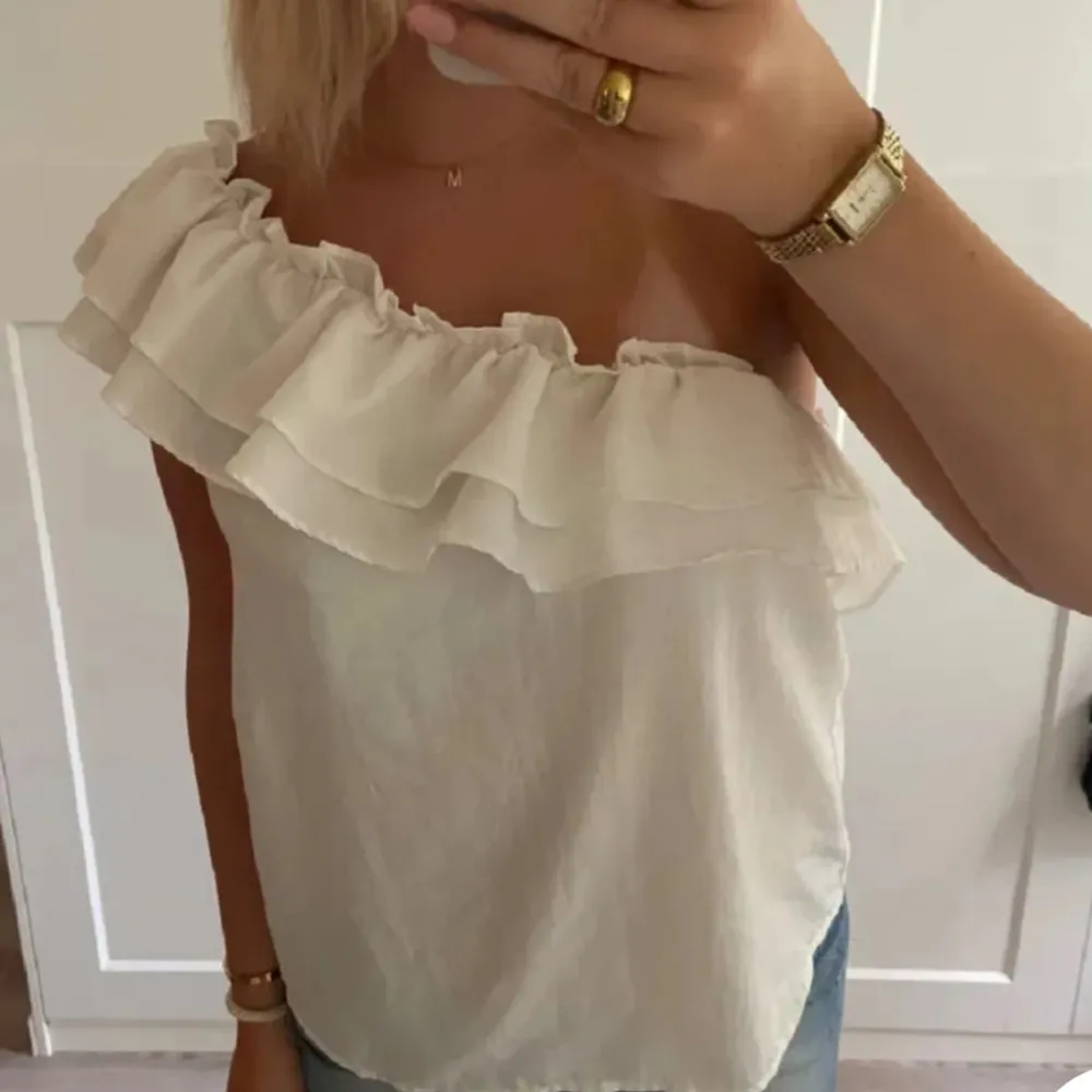 Säljer en superfin vit offshoulder topp med volangdetaljer. Perfekt för sommardagar eller en festlig kväll. Toppen är luftig och bekväm, vilket gör den idealisk för varma dagar. Säljer pga den inte passa!💘. Toppar.