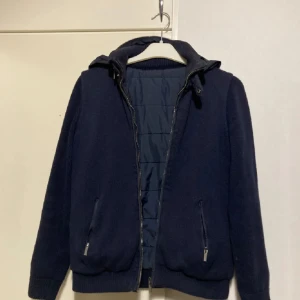 Massimo Dutti Cardigan - Säljer en snygg mörkblå jacka från Massimo Dutti. Den har en quiltad design framtill och en avtagbar huva. Perfekt för höst och vår! Jackan har dragkedja och ribbstickade muddar för extra komfort. Passar både till vardags och lite finare tillfällen. Passar mellan 160-170, jag är 173 och är på gränsen för liten.