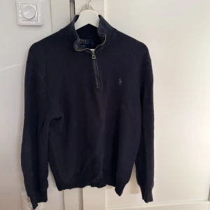 Marinblå tröja från Polo Ralph Lauren - Säljer en stilren svart tröja från Polo Ralph Lauren i pima bomull. Tröjan har en dragkedja vid halsen och det klassiska broderade logotypen på bröstet. Perfekt för både höst och vinter. Passar till både vardag och lite finare tillfällen.