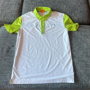 Vit och limegrön pikétröja från Puma - Säljer en snygg vit och limegrön pikétröja från Puma. Perfekt för sportiga aktiviteter med sin lätta och bekväma passform. Tröjan har korta ärmar och en klassisk krage med knappar. Baksidan har ett coolt mönster i olika färger. Passar perfekt för vår och sommar! Pris går allltid att förhandlas!