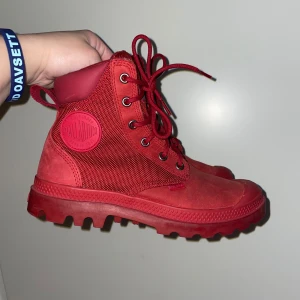 Röda boots från Palladium - Säljer ett par snygga röda boots från Palladium i mycket bra skick. De har en robust sula och snörning framtill. Perfekta för höst och vinter med sitt slitstarka material Skaft: skinn - Nubuck,Textil. Passar både till vardags och lite tuffare äventyr. Skorna är i storlek 37, tycker dom är lite små så passar även 36. 