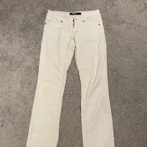 Vita jeans - Säljer ett par vita lågmidjade jeans i mycket bra skick. De har en klassisk femficksdesign och en rak passform. Perfekta för både vardag och festliga tillfällen. Passar bra till alla säsonger!