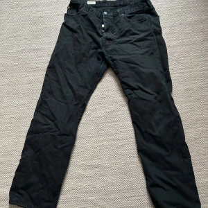 Svarta jeansbyxor från Levi's - Säljer ett par svarta jeansbyxor från Levi's i bra skick. W36/L32, de har en klassisk design med knappar och är tillverkade i 100% bomull. Perfekta för både vardag och fest. Passar bra till höst- och vintergarderoben.
