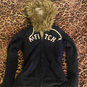 Mörkblå hoodie med päls från A&F - Mysig mörkblå hoodie från A&F med dragkedja och fluffig päls i runt luvan. Jättebra skick, köpte för 650kr skulle säga att den är i storlek S/M💕