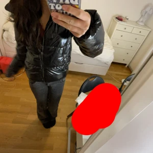Svart glansig pufferjacka - Säljer en svart glansig pufferjacka i mycket bra skick nästan helt oanvänd . Den har en dragkedja framtill och en mysig huva. Perfekt för kyliga dagar och ger en cool look. Jackan är varm och bekväm, idealisk för både höst och vinter.