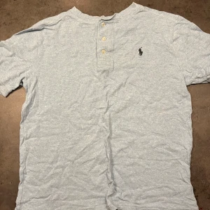 Ljusblå t-shirt från Ralph Lauren - Säljer en ljusblå t-shirt från Ralph Lauren i bra skick. Den har korta ärmar och en liten broderad logga på bröstet. Perfekt för en avslappnad stil. Passar både till vardags och fest! Storlek XS eller 14-15 år. Nypris 500:-
