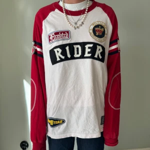 Vit och röd långärmad tröja från Firebird - cool vit och röd långärmad tröja från. Tröjan har texten 'RIDER' på framsidan och 'WILLIAMS' på baksidan. Den har också flera patches och detaljer som gör den unik. Tröjan är i storlek XL men är själv storlek S och kunnat använda den oversized💕