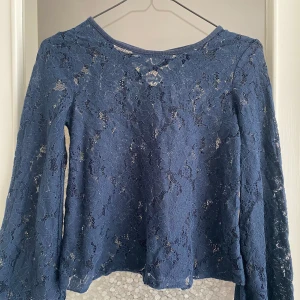 Blå spetsblus med långa ärmar - Säljer en superfin blå spetsblus med långa ärmar. Blusen har en vacker spetsdesign och en snygg snörning på ryggen. Perfekt för både vardag och fest! 💙