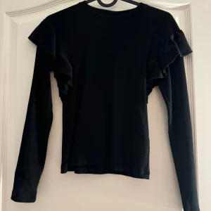 Gina Young tröja - Svart Gina Young tröja med volanger på armarna i stolek 158/164. Säljer pågrund av att den är för liten för mig. Säljs för 100kr. Köpare står för frakten.