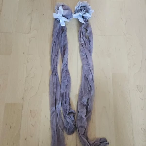 Beige knästrumpor med spetsdetaljer - Säljer ett par snygga gråa knästrumpor med vita spetsdetaljer.. De är i nyskick och perfekta för att ge en elegant touch till din outfit.